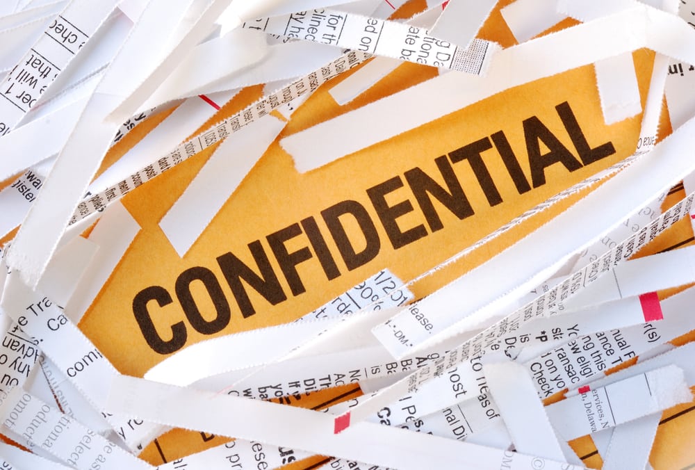 A bunch of shredded papers with the word confidential written on it.